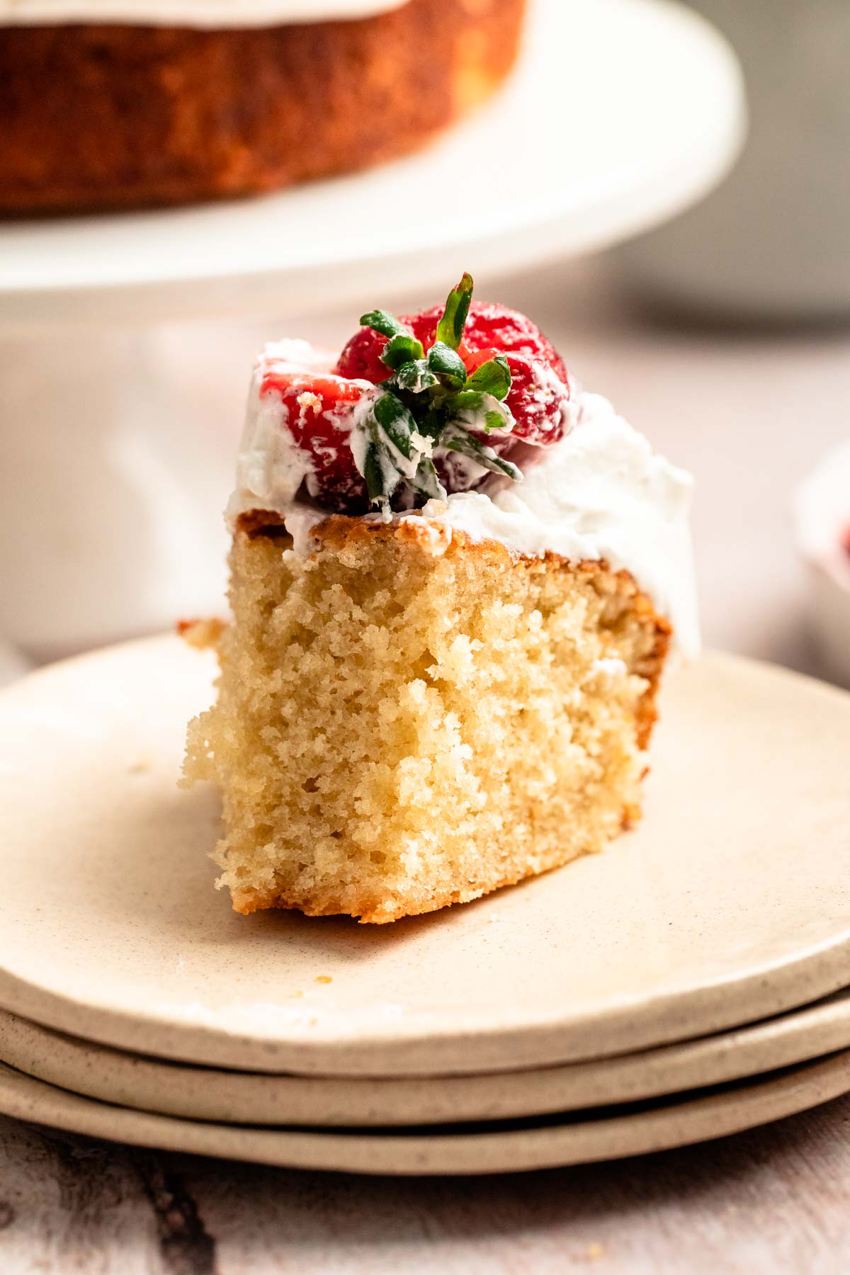 Bite missing from a slice of strawberry whipped cream cake.