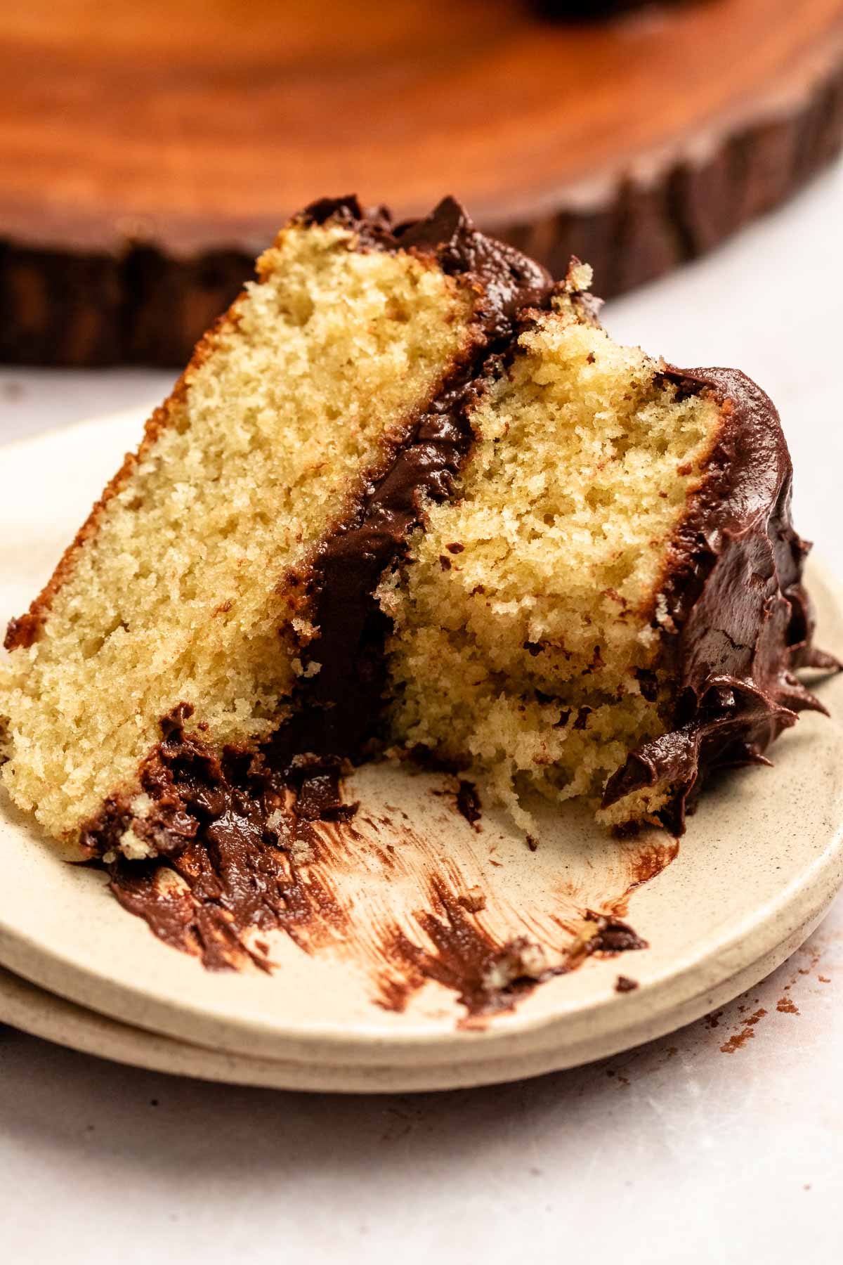 Bite missing from a slice of vanilla cake with chocolate frosting.