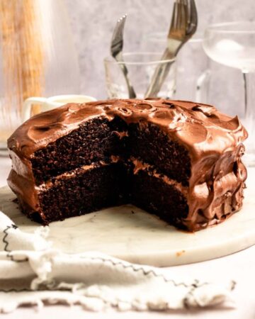 Slice missing from a chocolate cake with chocolate cream cheese frosting.