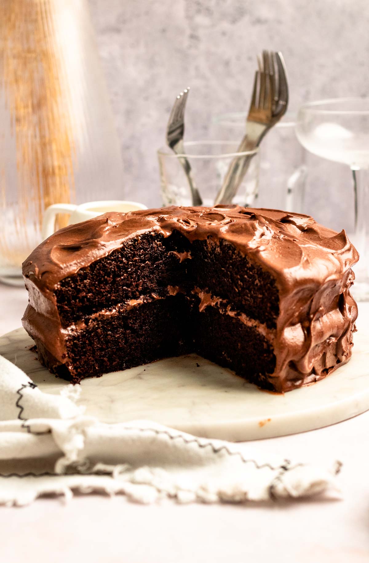 Slice missing from a chocolate cake with chocolate cream cheese frosting.