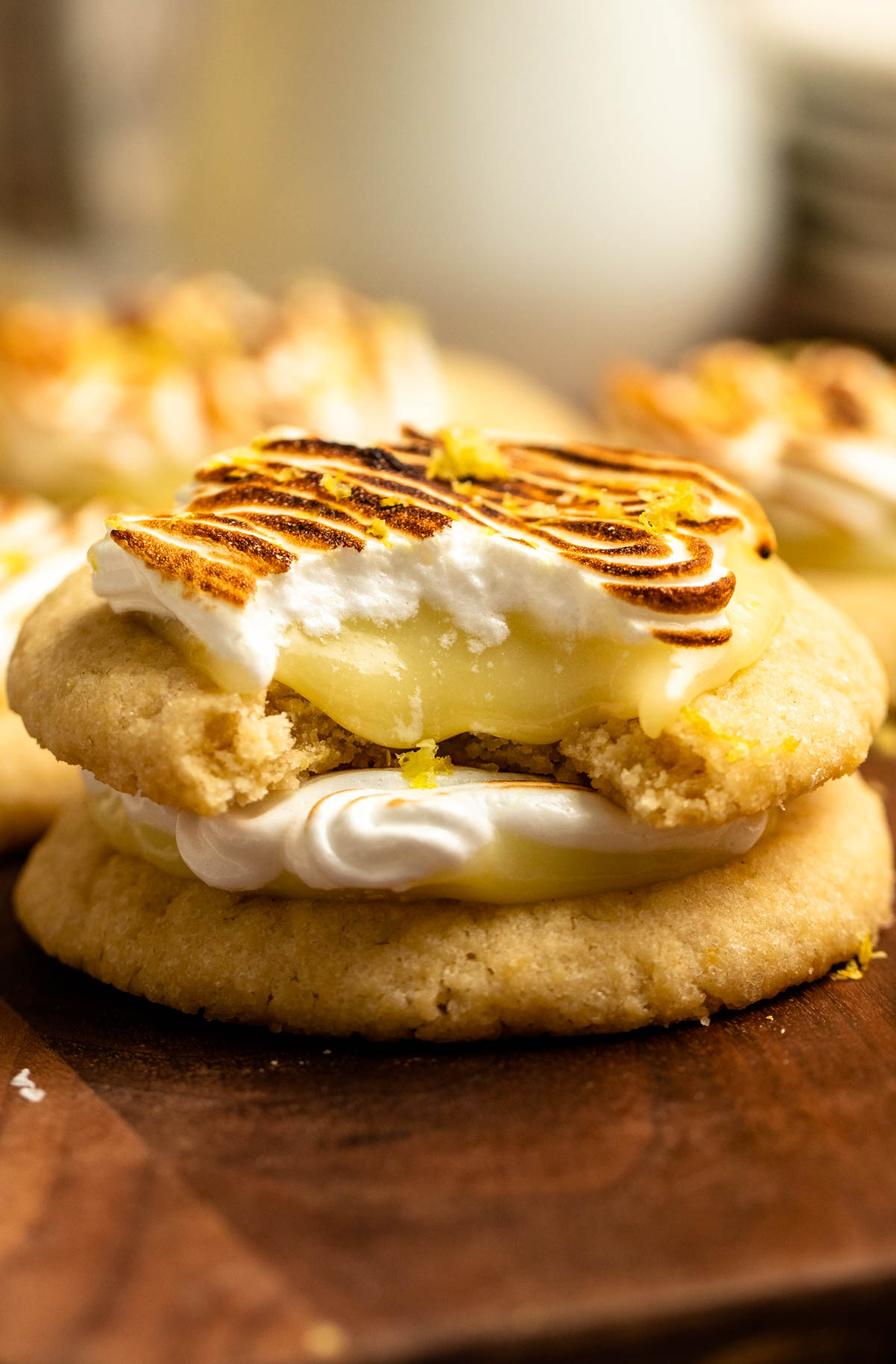 A stack of two lemon meringue cookies with the top one with a bite missing.