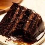 Slice missing from a chocolate cake with chocolate mousse.