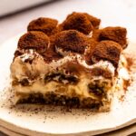Slice of Italian tiramisu with cocoa powder on top.
