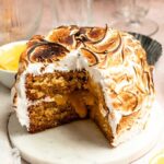 Slice missing from a lemon meringue cake on a cake plate.
