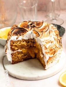 Slice missing from a lemon meringue cake on a cake plate.