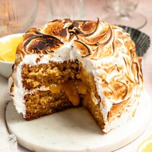 Slice missing from a lemon meringue cake on a cake plate.