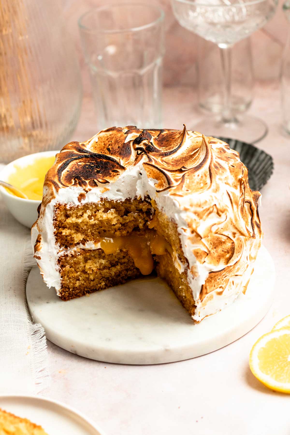 Slice missing from a lemon meringue cake on a cake plate.