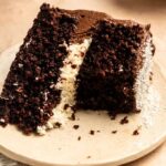 Bite missing from a coconut chocolate cake.