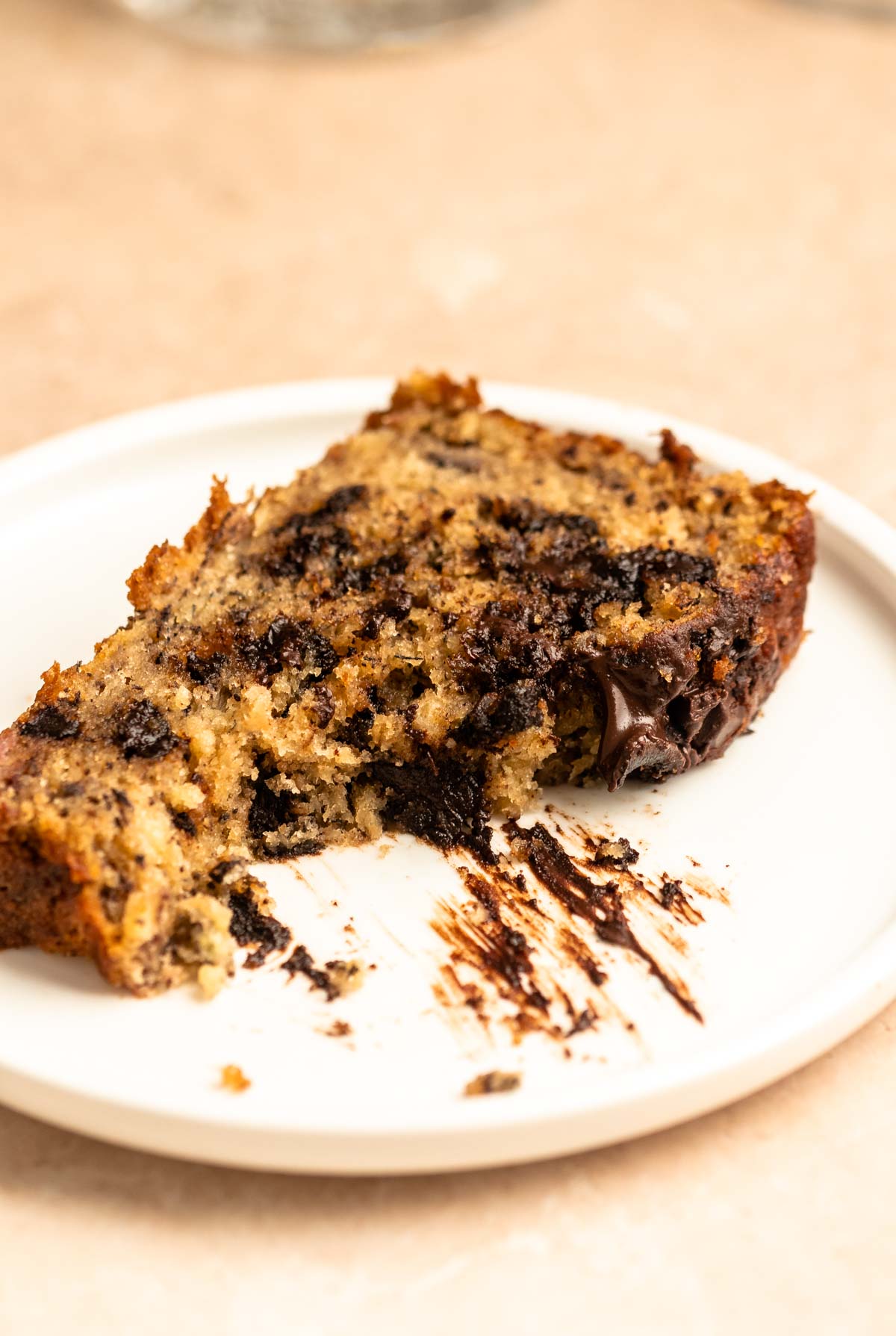 Slice of chocolate chunk banana bread on a plate with a bite missing.