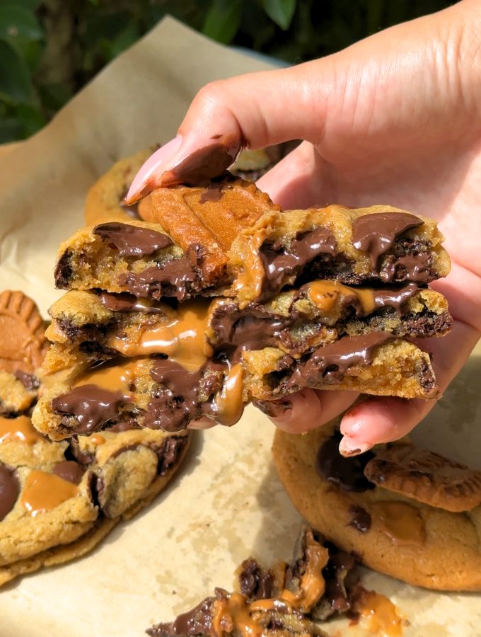 A hand holding a neat stack of Biscoff butter cookie halves, displaying the thick, chewy layers and spiced cookie crumbs on top.
