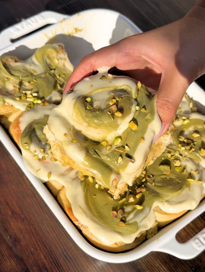 Hand holding a pistachio cinnamon roll.