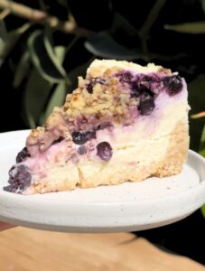 Slice of blueberry crumble cheesecake on a plate.