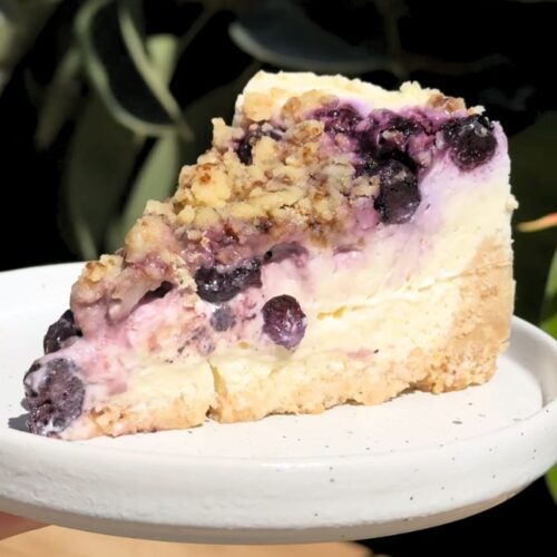 Slice of blueberry crumble cheesecake on a plate.