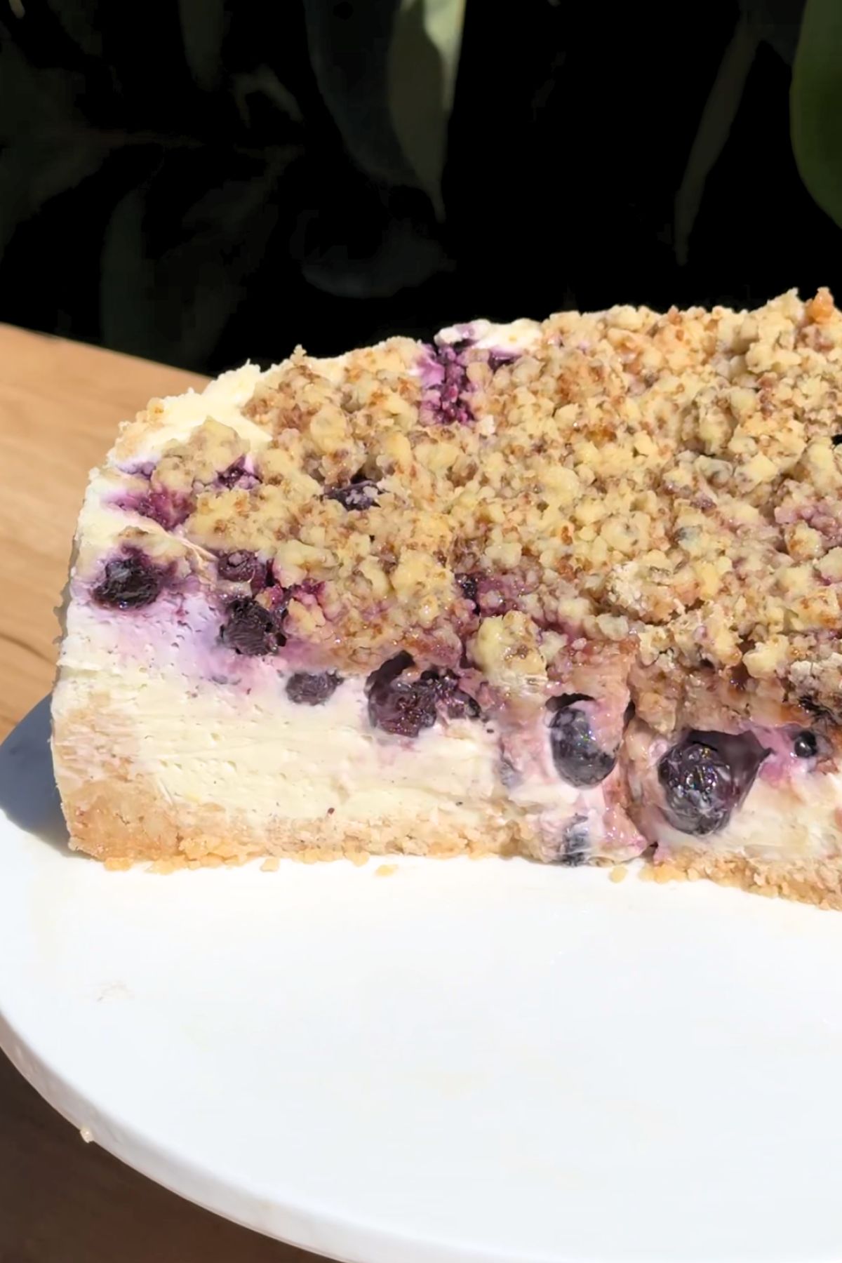 Slice missing from a blueberry crumble cheesecake on a cake plate.