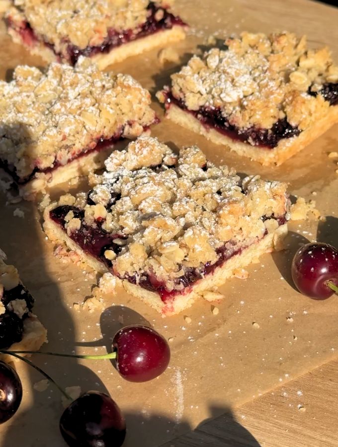 Slice of cherry pie bars on brown parchment paper.