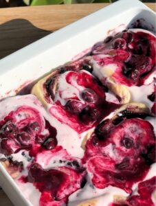 Blueberry cinnamon rolls with cream cheese frosting and blueberry sauce on top.