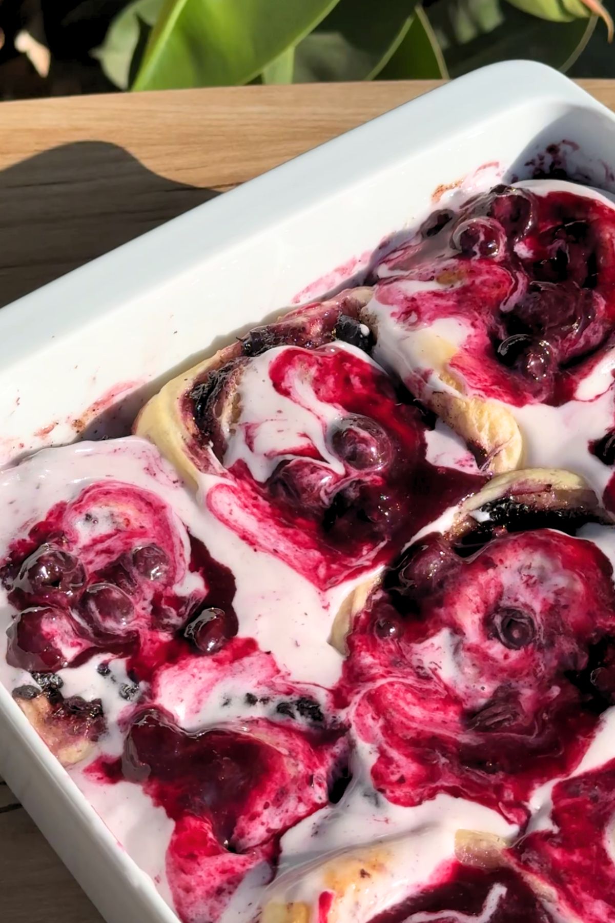 Blueberry cinnamon rolls with cream cheese frosting and blueberry sauce on top.