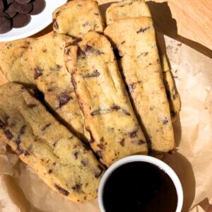 Chocolate chip cookie fries on a plate next to a bowl with chocolate sauce.