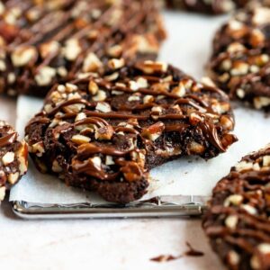 Turtle cookies on a white parchment paper with the middle one missing a bite.