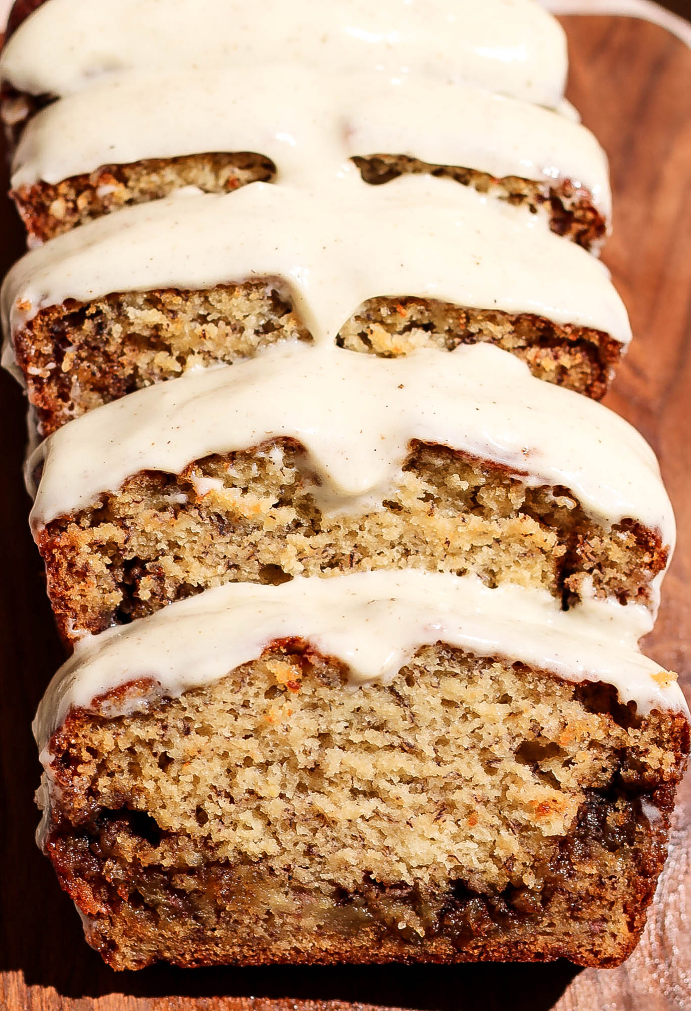 Close-up view of sliced cinnamon roll banana bread showing the moist crumb and thick layer of cream cheese frosting.