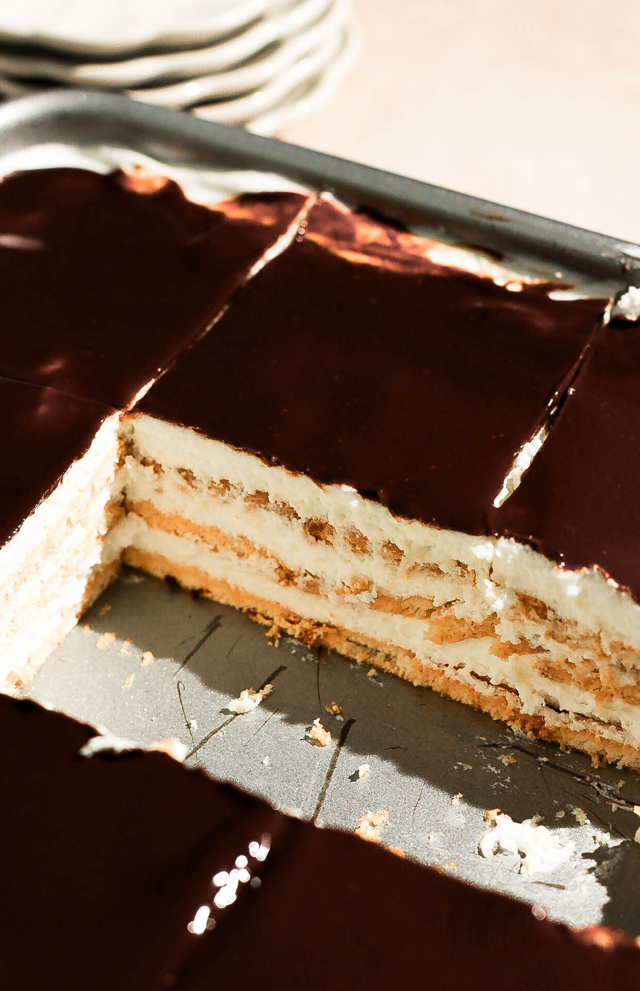 A baking pan of chocolate eclair cake with one slice removed, displaying the clean layers inside the pan.