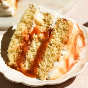 Close-up view of a single slice of layered salted caramel cake on a small decorative plate.