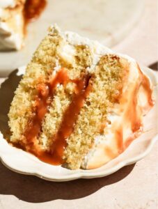 Close-up view of a single slice of layered salted caramel cake on a small decorative plate.