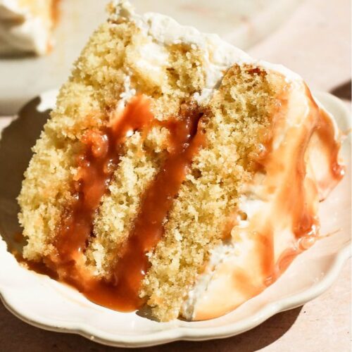 Close-up view of a single slice of layered salted caramel cake on a small decorative plate.
