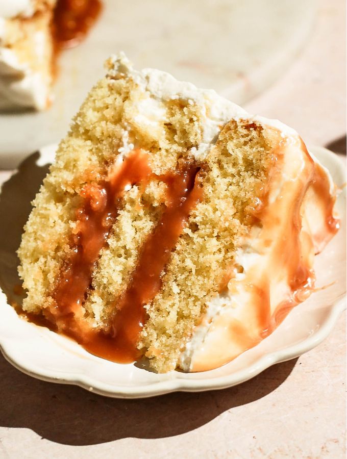 Close-up view of a single slice of layered salted caramel cake on a small decorative plate.