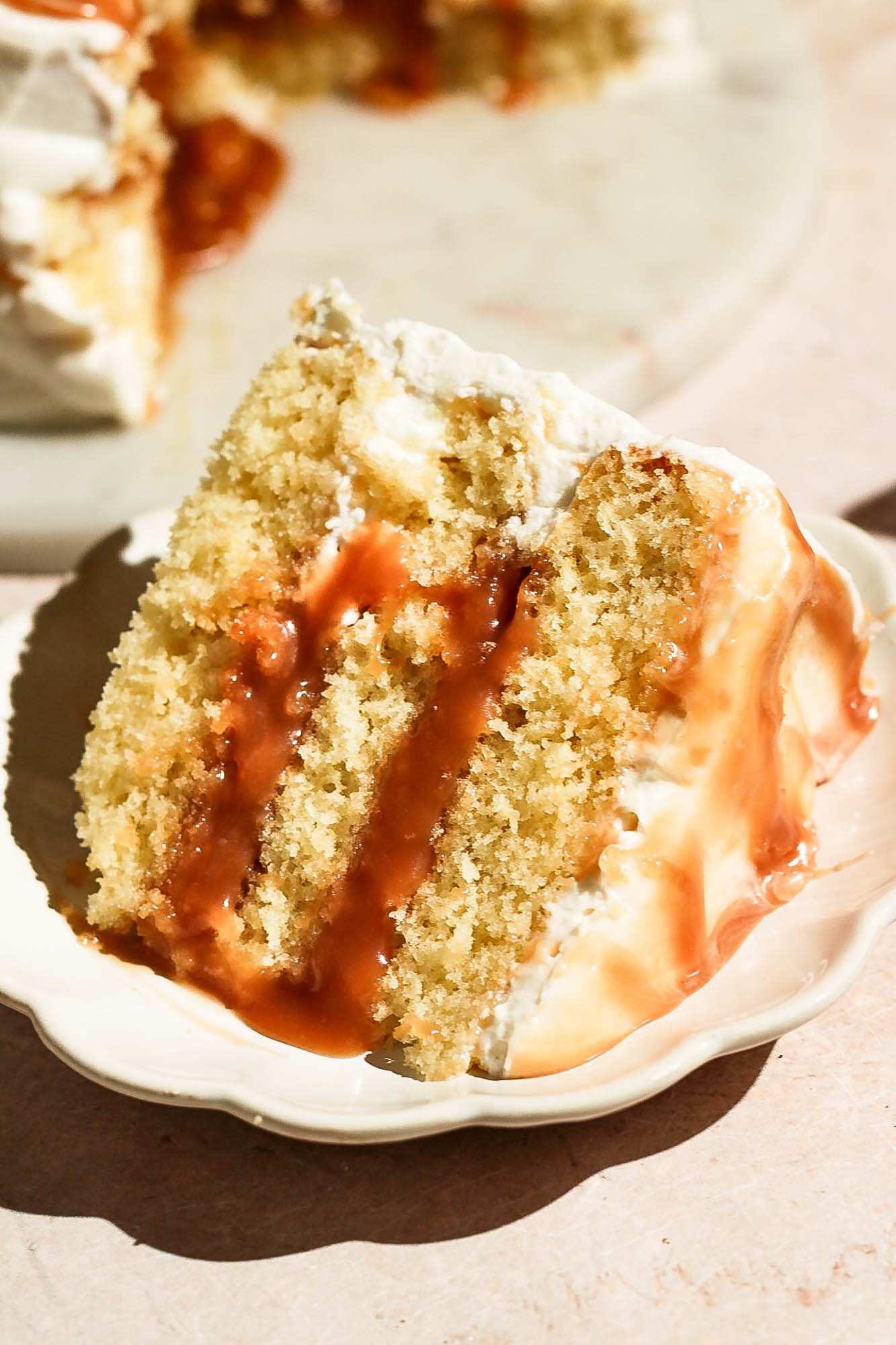 Close-up view of a single slice of layered salted caramel cake on a small decorative plate.