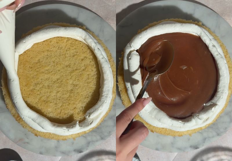 Piping a cream cheese frosting border onto a cake layer and spreading salted caramel filling inside.
